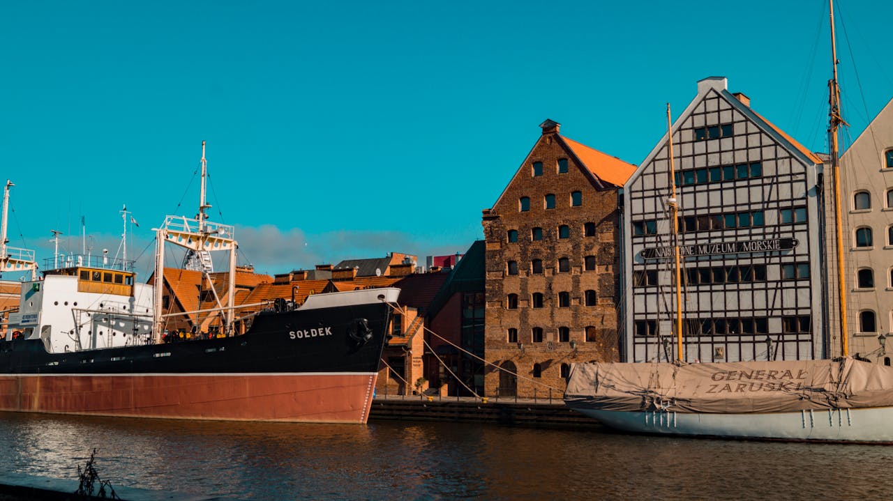 Vessels docked at Gdańsks Maritime Museum under a clear sky, showcasing historic architecture.